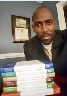 Co-author displaying a stack of hardcover leadership books he contributed to