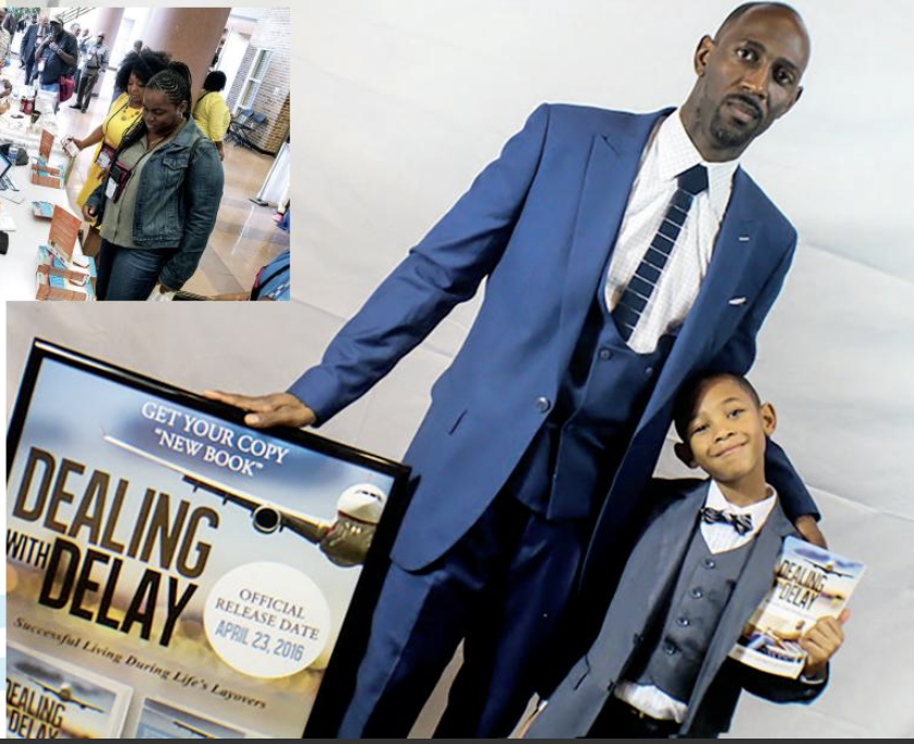 Co-author in a blue suit and his son in a gray vest beside a framed 'Dealing With Delay' launch poster